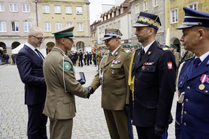 Komendant Warmińsko-Mazurskiego Oddziału Straży Granicznej wraz z Wojewodą Warmińsko-Mazurskim Radosławem Królem wręczają pamiątkowe emblematy W-MOSG Komendant Warmińsko-Mazurskiego Oddziału Straży Granicznej wraz z Wojewodą Warmińsko-Mazurskim Radosławem Królem wręczają pamiątkowe emblematy W-MOSG